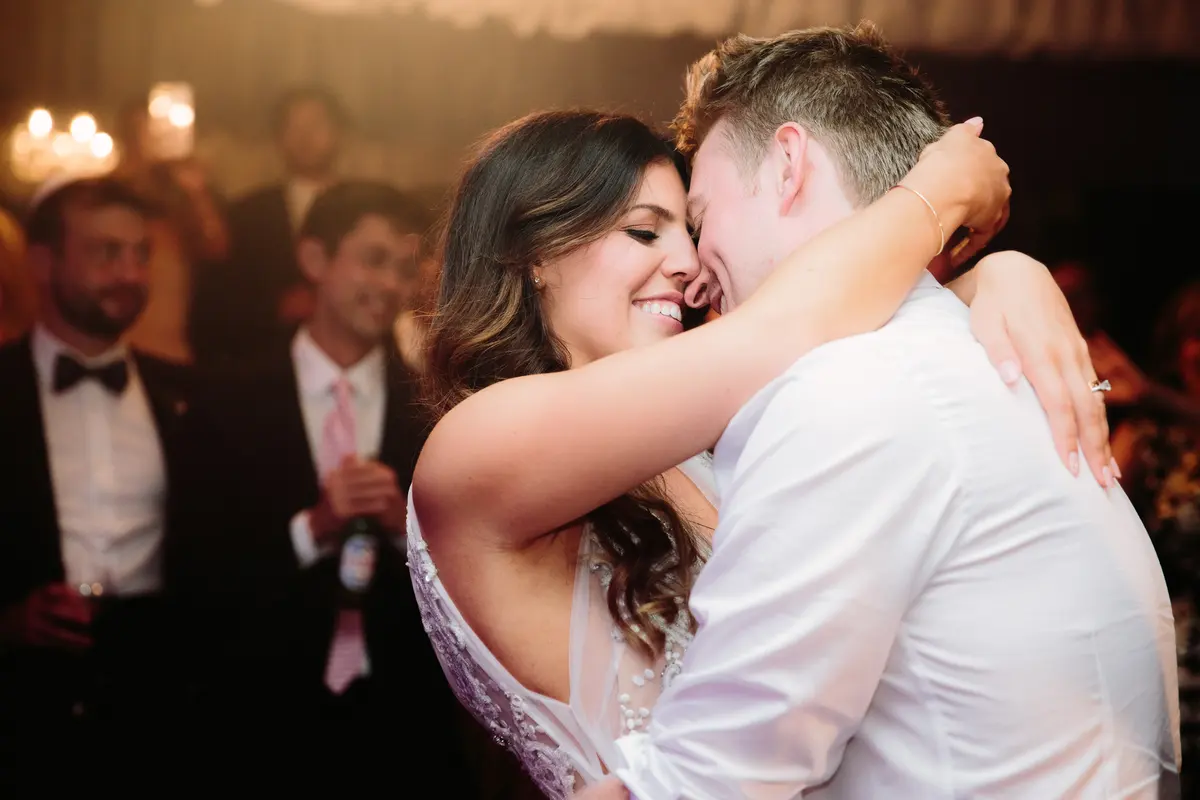 Bride and groom in a close embrace, smiling cheek to cheek, during their first dance