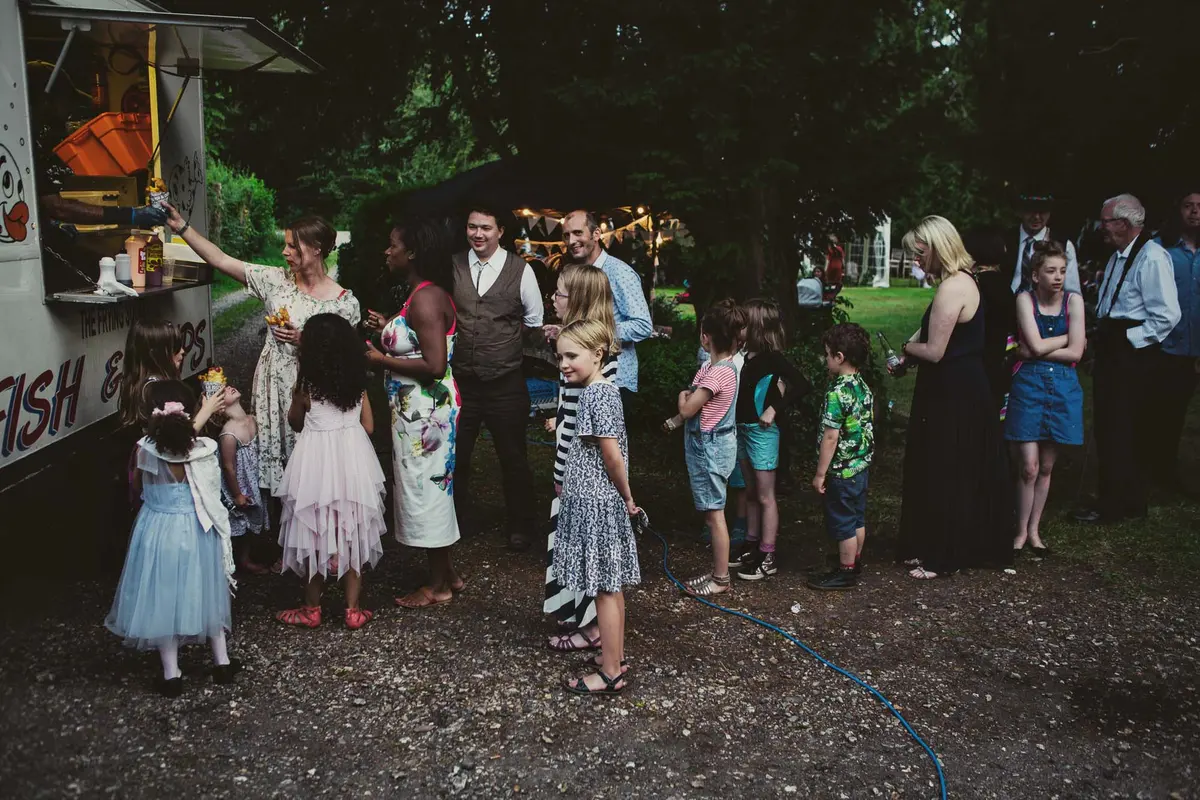 Guests and children queuing at a fish and chip van in the evening