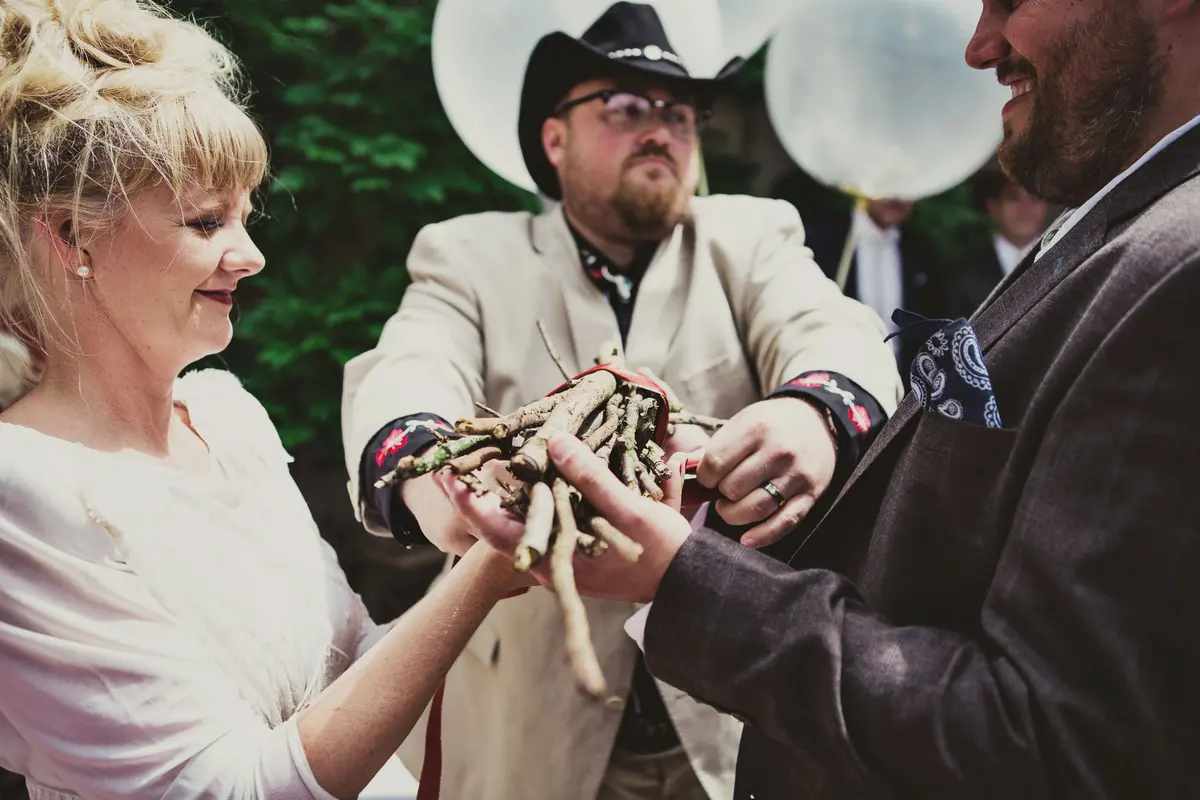 Bride and groom holding a bundle of tied sticks together during their ceremony