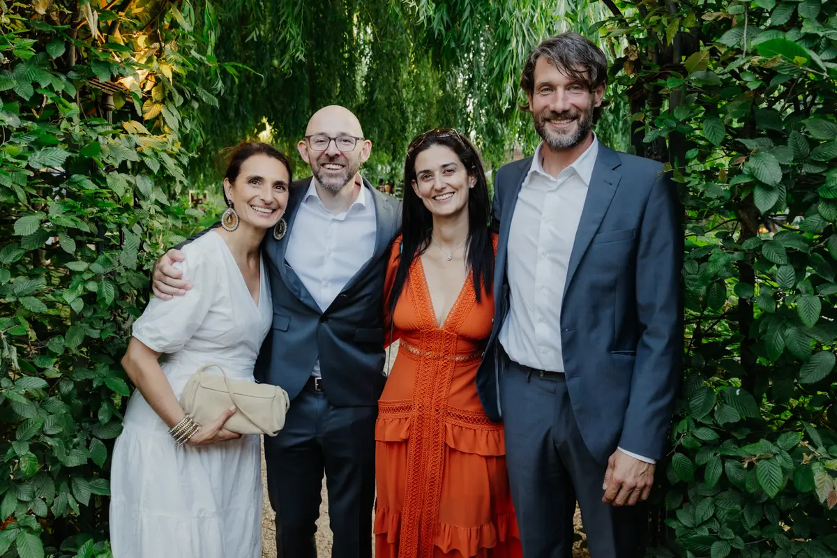 Four wedding guests smiling together in front of green foliage at the Perch