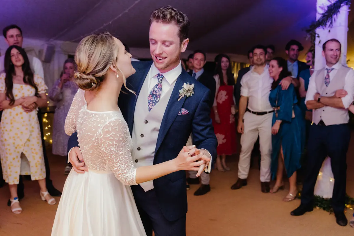 Bride and groom dancing their first dance as guests look on in the marquee at the Perch