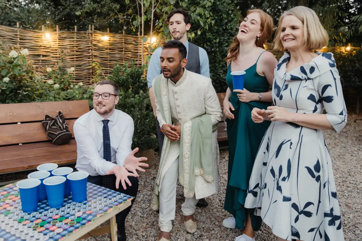 Guests laughing around a game of beer pong in the garden at the Perch