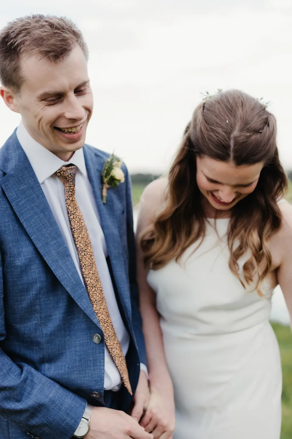 Close-up of the groom and bride laughing together, both looking down