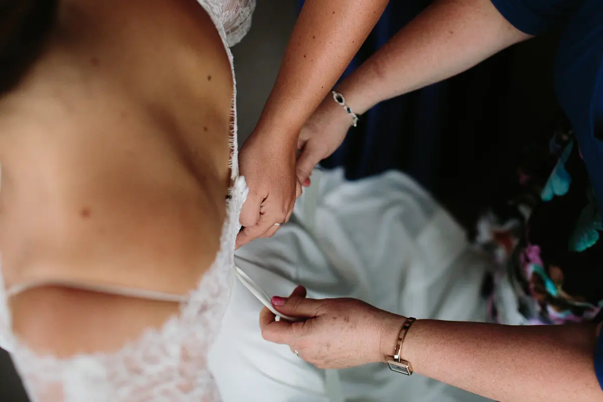 Bride doing up dress - Oxford Weddings at Bodleian Library