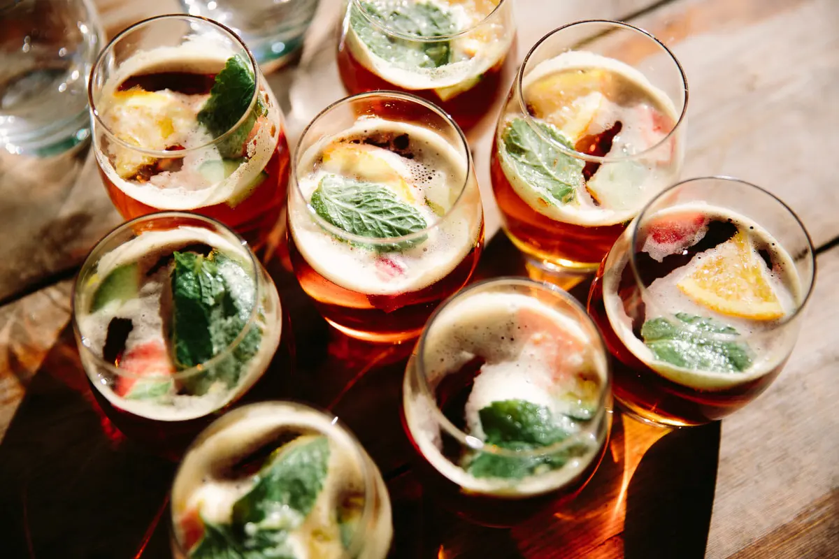 Glasses of fruit punch with mint, orange and strawberry on a sunlit wooden table