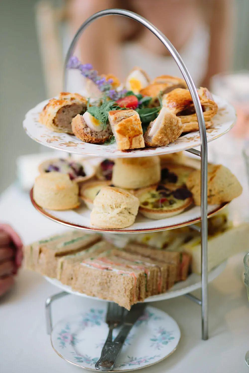 Three-tier stand of sandwiches, scones, quiches and sausage rolls for a wedding afternoon tea