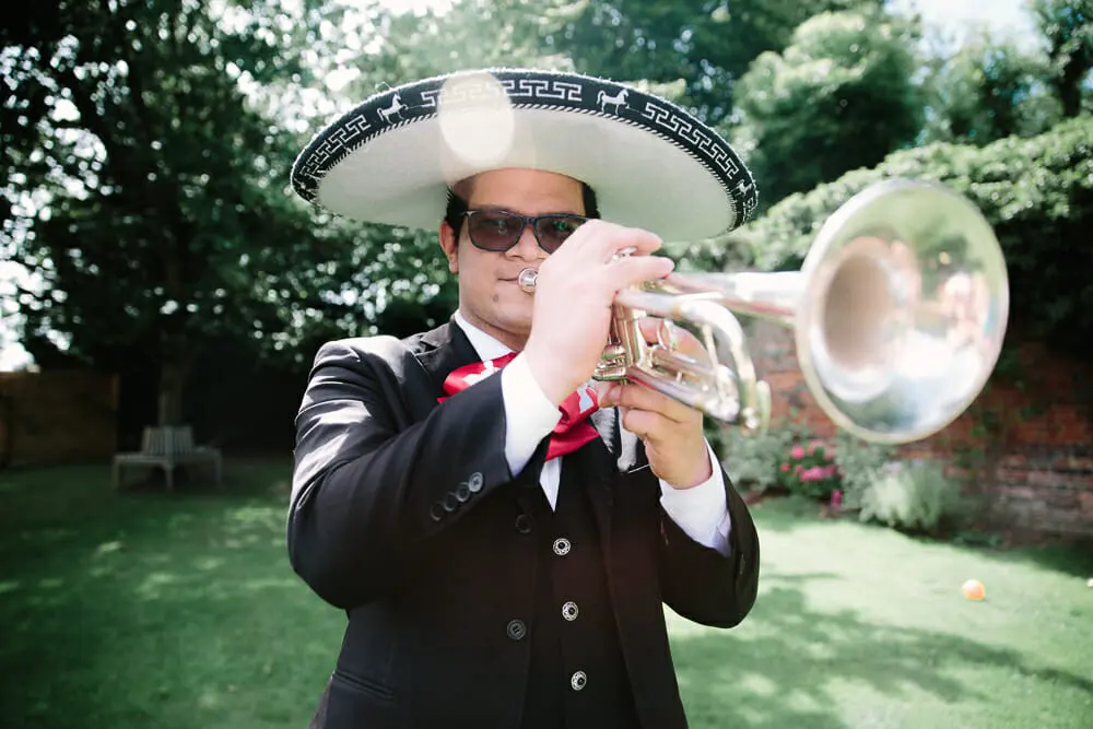 Mariachi musician in a sombrero playing a trumpet on a garden lawn