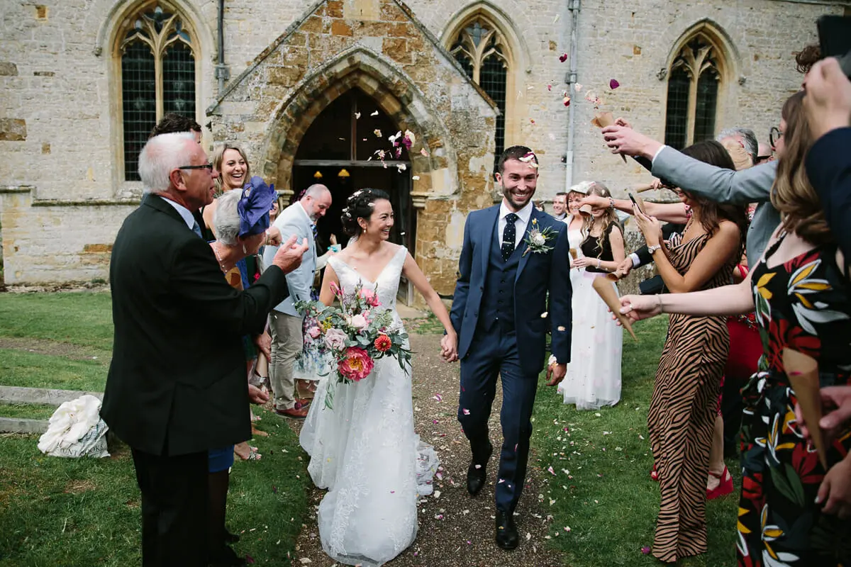 Guests throwing confetti over the bride and groom as they leave the church