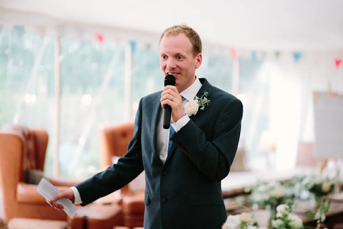 Groom holding his notes and a microphone during his wedding speech at the Perch