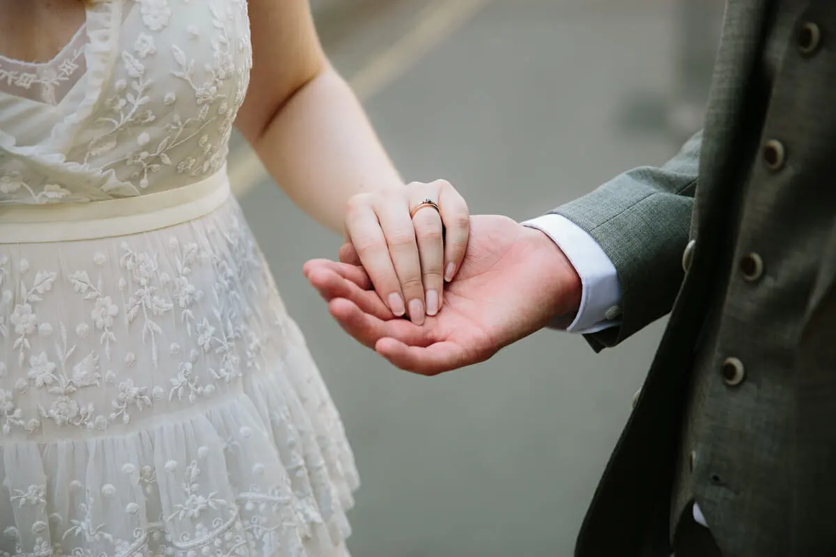 Close-up of the bride's hand with her ring resting in the groom's palm