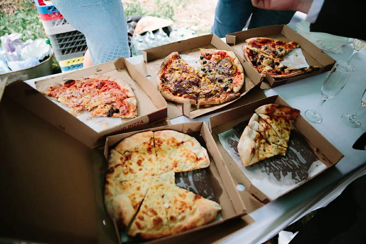 Boxes of takeaway pizza laid out on a table at an outdoor reception
