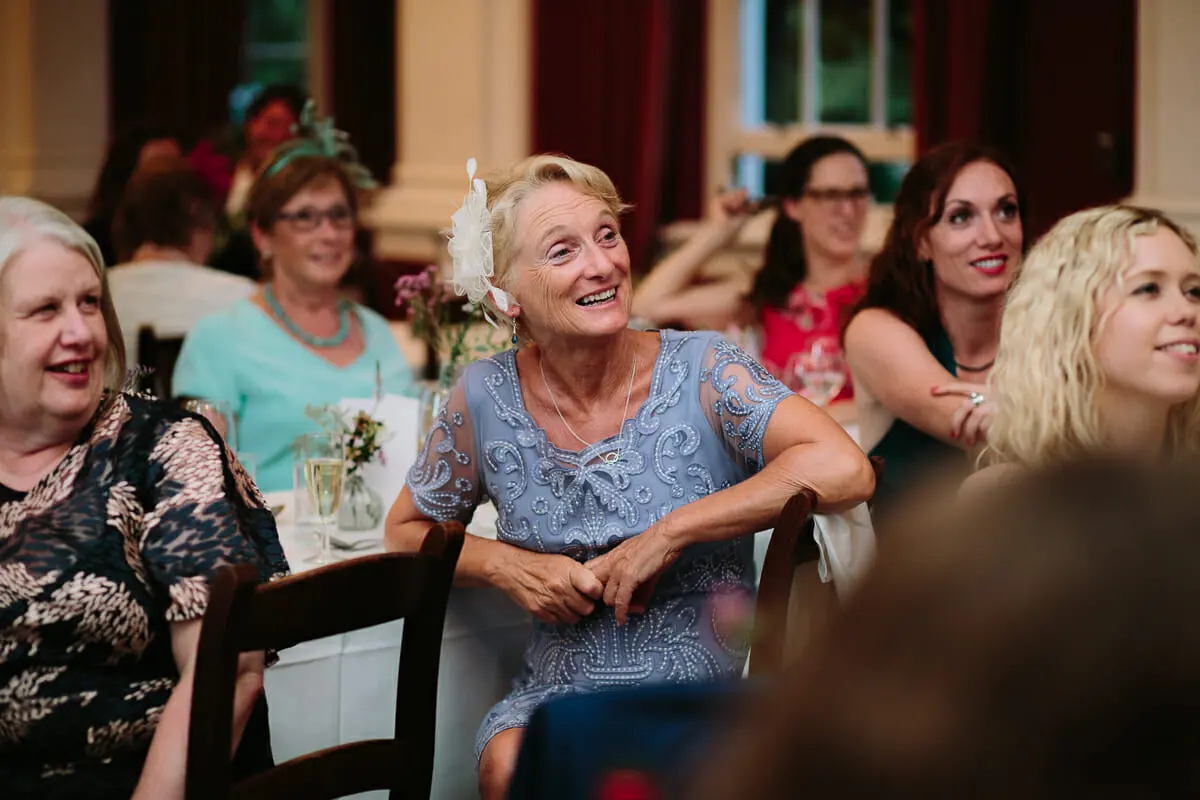 Smiling guests seated at the reception tables listening to the speeches