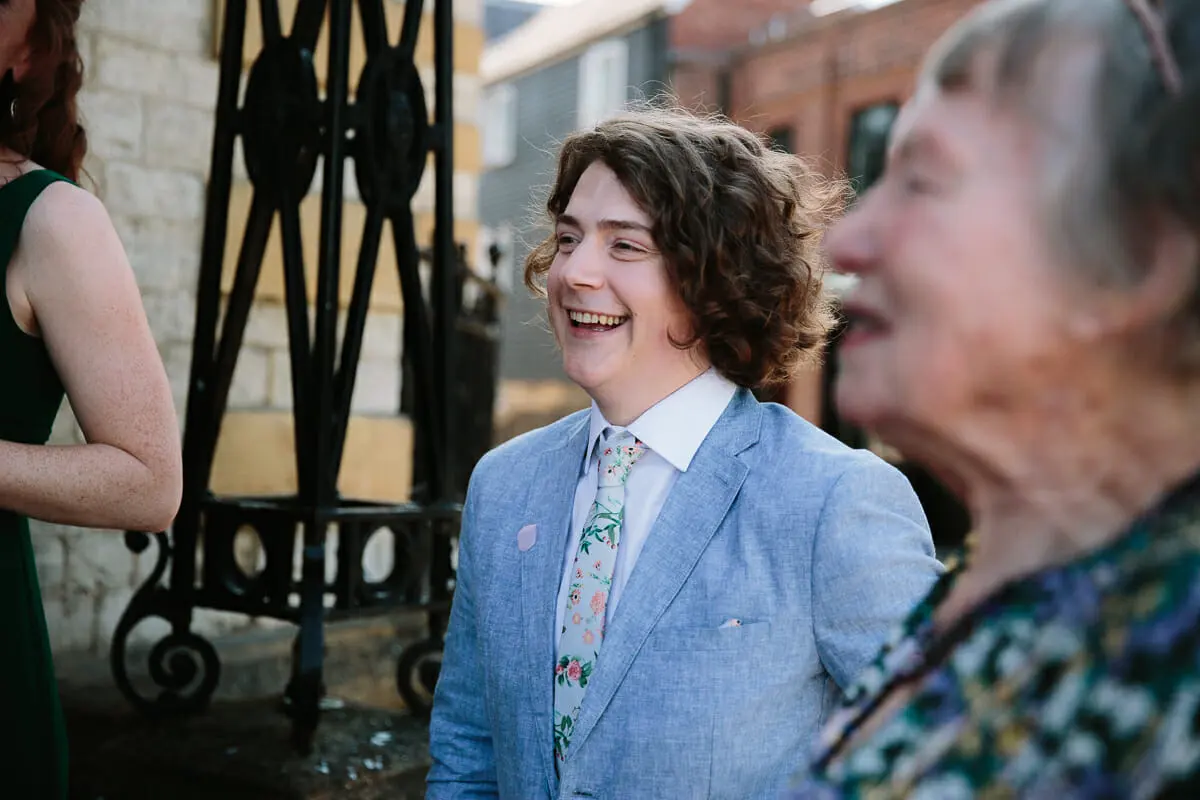 Guest in a pale blue suit and floral tie laughing outside the register office