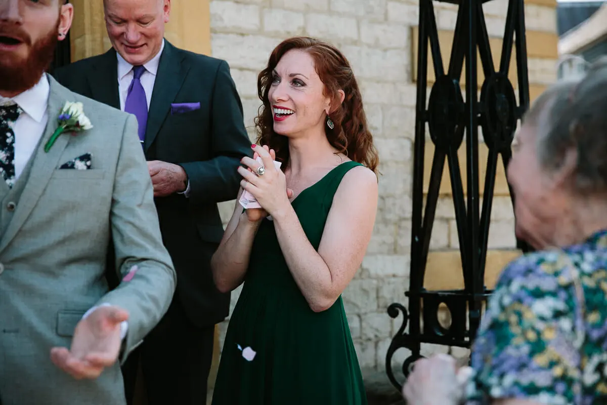 Guest in a green dress smiling and clapping outside the register office