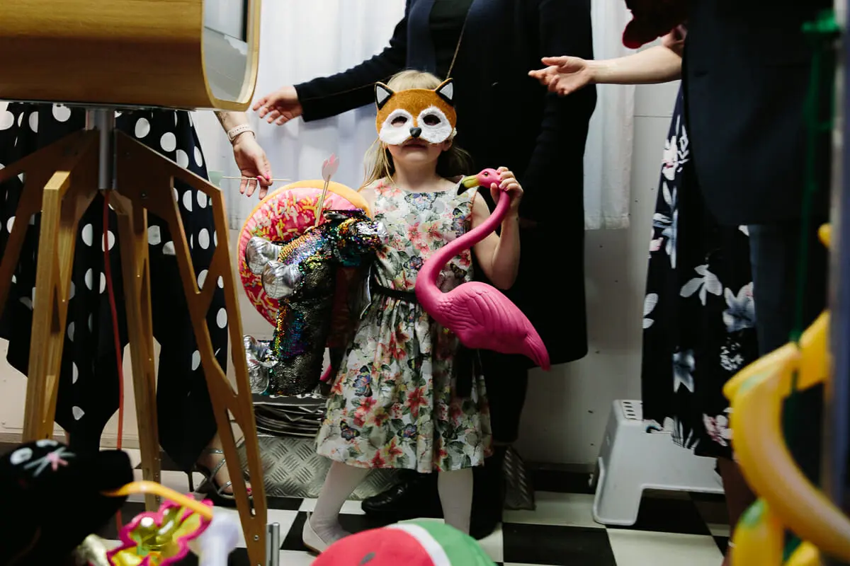 Young girl in a fox mask holding a pink flamingo prop by the photo booth