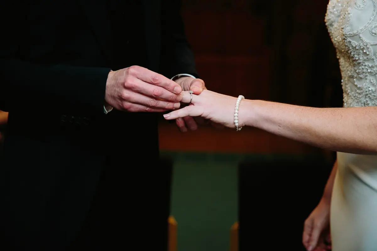 Groom sliding a wedding ring onto the bride's finger during the ceremony