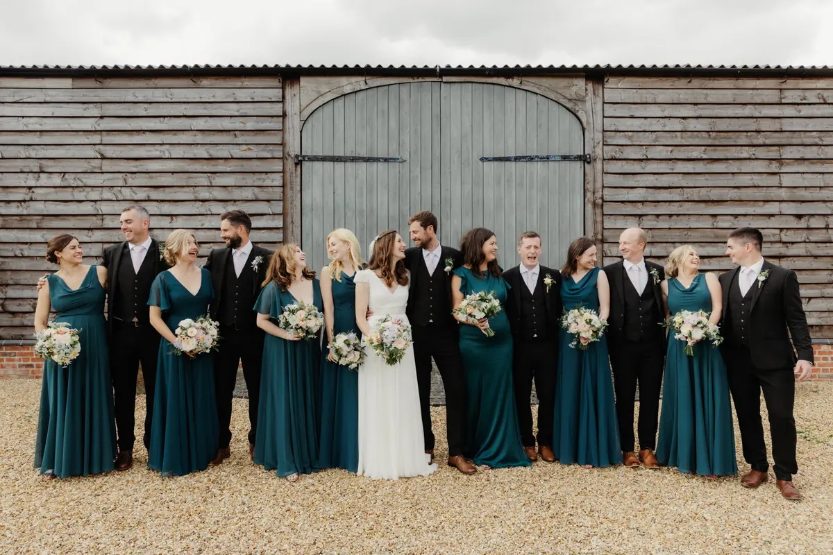 Bride and groom with bridesmaids in teal and groomsmen in front of the barn doors at Primrose Hill Farm