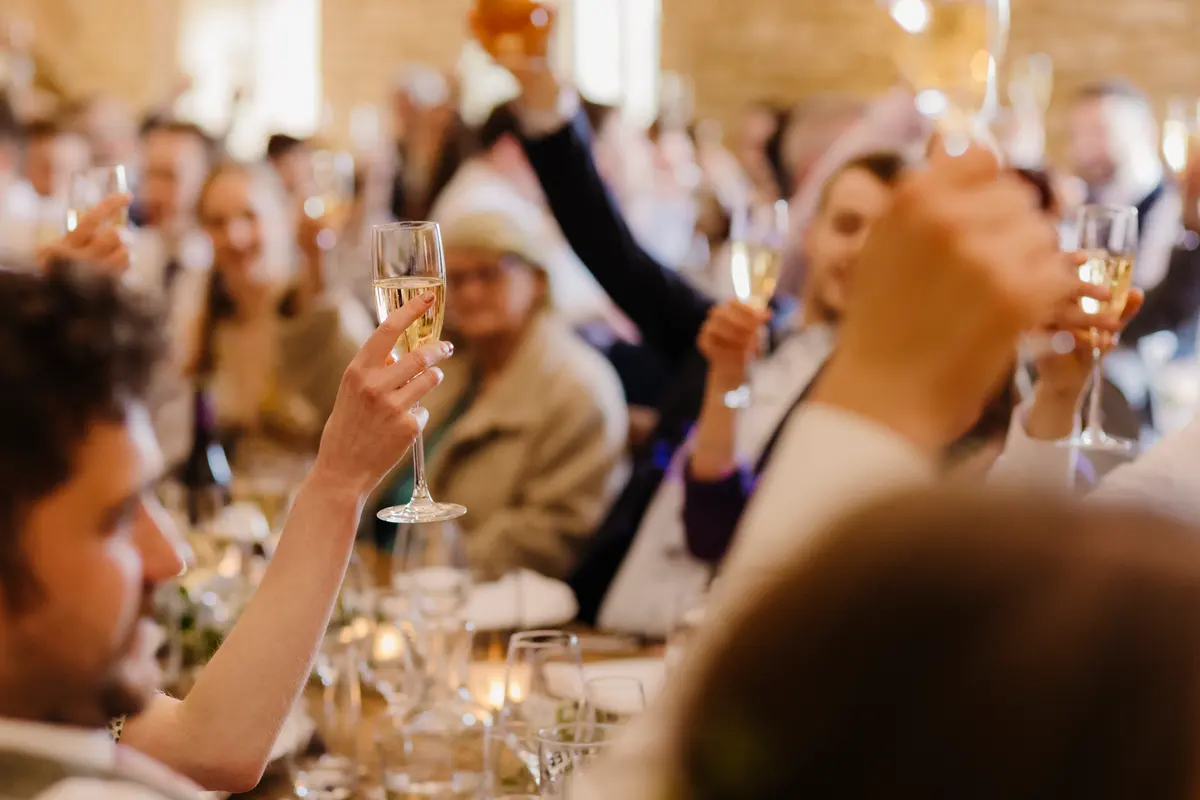 Guests raising glasses of fizz for a toast during the wedding breakfast at Caswell House