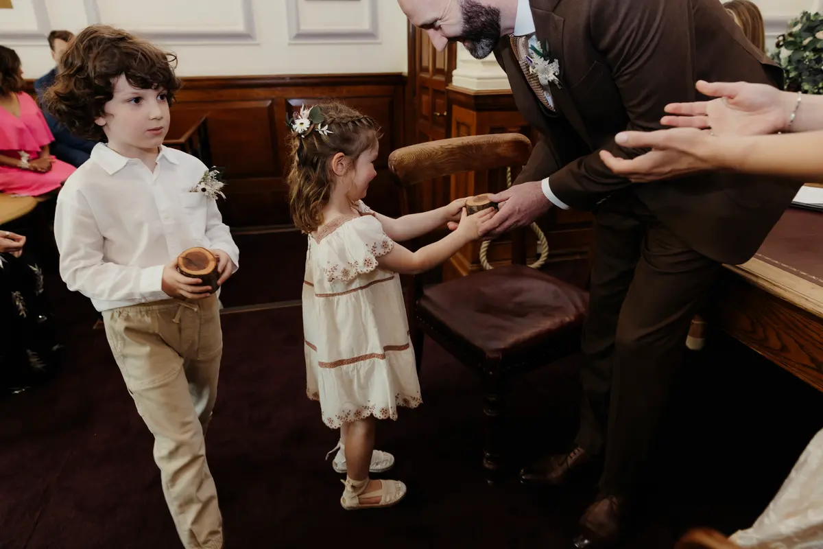 Flower girl handing a ring box to the groom as a page boy waits during the ceremony