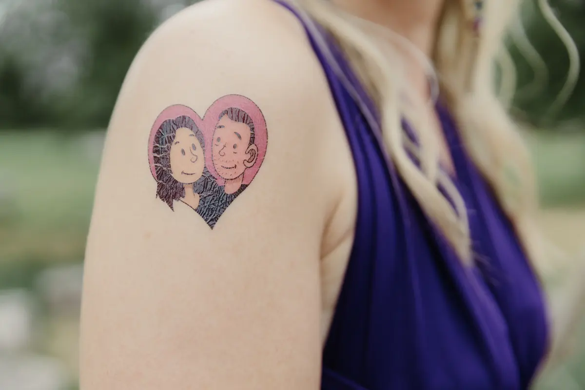 Temporary tattoo of a cartoon couple in a pink heart on a guest's shoulder