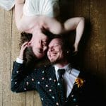 OXFORD TOWN HALL WEDDING - a couple in their wedding outfits posing for a photograph lying on the floor smiling.